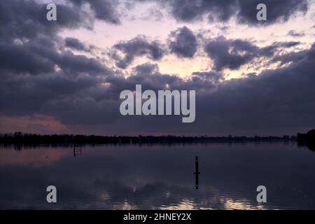 See mit Boys und der Himmel in der Dämmerung auf dem Wasser gegossen Stockfoto