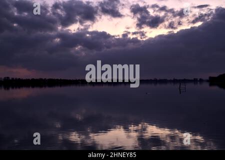 See mit Boys und der Himmel in der Dämmerung auf dem Wasser gegossen Stockfoto