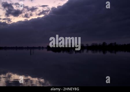 See mit Boys und der Himmel in der Dämmerung auf dem Wasser gegossen Stockfoto