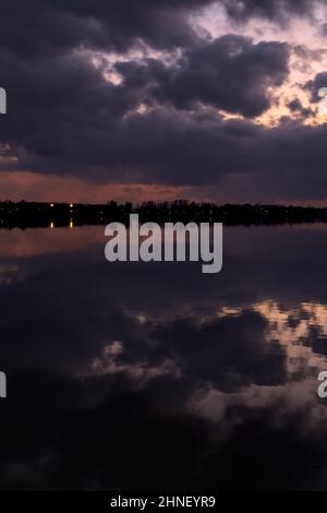 See mit Boys und der Himmel in der Dämmerung auf dem Wasser gegossen Stockfoto