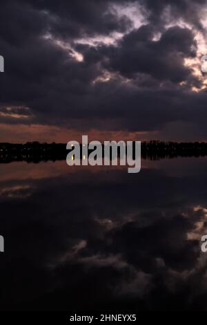 See mit Boys und der Himmel in der Dämmerung auf dem Wasser gegossen Stockfoto