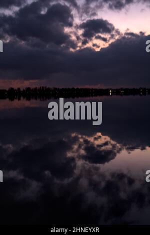 See mit Boys und der Himmel in der Dämmerung auf dem Wasser gegossen Stockfoto