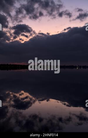 See mit Boys und der Himmel in der Dämmerung auf dem Wasser gegossen Stockfoto