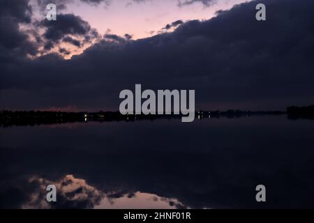 See mit Boys und der Himmel in der Dämmerung auf dem Wasser gegossen Stockfoto