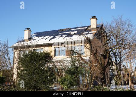 Im Winter in einem Schweizer Dorf auf dem Dach eines Familienhauses installierte Photovoltaik-Paneele oder Solarzellen. Stockfoto