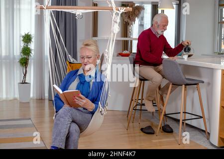 Schönes Seniorenpaar, das sich Zeit genommen hat, sich ausruhte, Kaffee getrunken und zu Hause gelesen hat. Stockfoto