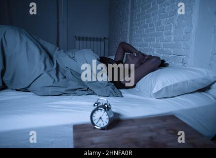 Schlaflos und verzweifelt schöne afro amerikanische Frau wach in der Nacht nicht in der Lage zu schlafen Blick auf Uhr leiden an Schlaflosigkeit in Schlafstörungen und Stockfoto