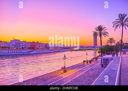 SEVILLA, SPANIEN - 29. SEPTEMBER 2019: Die violette Dämmerung über dem Guadalquivir-Fluss mit Silhouetten von Palmen, Torre Sevilla und dem alten Triana-Viertel Stockfoto