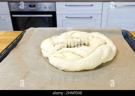 Roher herzhafter Weihnachtskuchen in Form eines Kranzes, gefüllt mit Quark, Spinat und gesalzenem rotem Fisch auf einem Backblech. Stockfoto