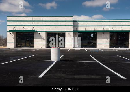 Horizontale Aufnahme eines frisch gestreiften Parkplatzes vor einem neuen Einkaufszentrum im Bau. Stockfoto