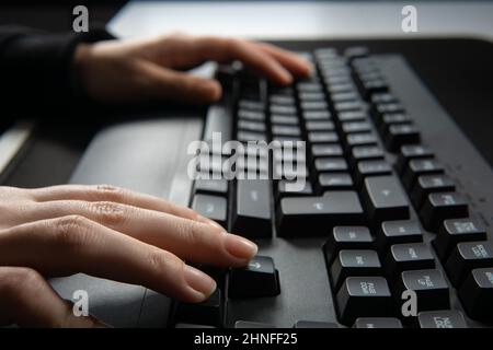 Nahaufnahme der Frau, die auf der Computertastatur tippt und auf dem Tisch im Internet surft. Stockfoto