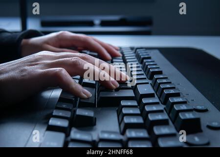 Nahaufnahme der Frau, die auf der Computertastatur tippt und auf dem Tisch im Internet surft. Stockfoto
