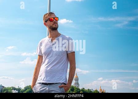 Stilvoller junger Mann mit Sonnenbrille und Händen in den Taschen Stockfoto
