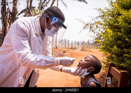 Ein afrikanischer Arzt führt einen Abstrichtest an einem Kind durch, um zu sehen, ob es positiv auf das Coronavirus ist. Covid-19-Test in Afrika. Molekularer und schneller Antigentest Stockfoto