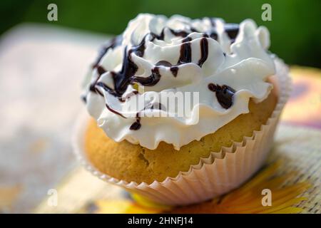 Hausgemachter Muffin mit Schlagsahne und Schokolade in einem Pappbecher. Stockfoto