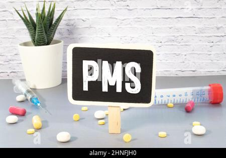 Die Inschrift Text auf der grauen Tafel, PMS Premenstrual-Syndrom mit handgezeichneten glücklich und traurig emojis. Mit farbigen Kreidestücken. Stockfoto