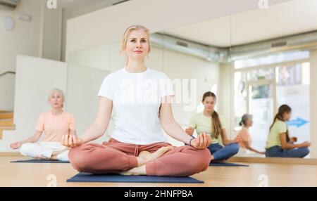 Gruppe von Frauen und Teenager Mädchen tun Yoga Padmasana Übung, Lotus Pose Stockfoto