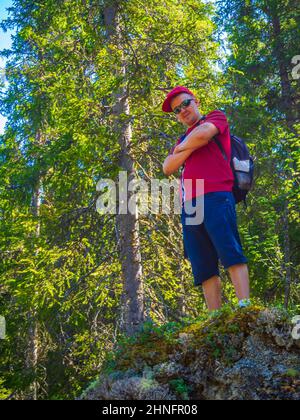 Der junge Reisende Tourist steht auf einem riesigen Felsen in der natürlichen norwegischen Landschaft in Hemsedal Viken Norwegen. Stockfoto