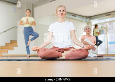 Gruppe von Frauen und Teenager Mädchen tun Yoga Padmasana Übung, Lotus Pose Stockfoto