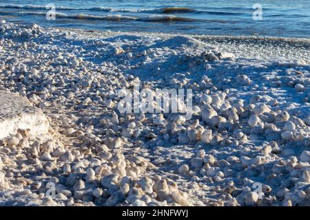 Schnee, Frost und Wind erzeugen unregelmäßig geformte Eisbälle am Ufer des Lake Michigan Stockfoto