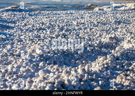 Schnee, Frost und Wind erzeugen unregelmäßig geformte Eisbälle am Ufer des Lake Michigan Stockfoto