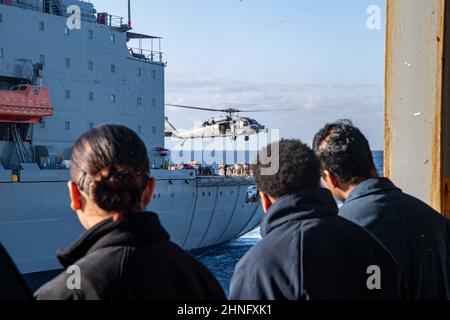 PHILIPPINISCHES MEER (Feb 15, 2022) ein MH-60s Sea Hawk Hubschrauber vom Helicopter Sea Combat Squadron (HSC) 25 führt eine vertikale Nachfüllung mit dem Flottennachfüller USNS Yukon (T-AO 202) durch. Amerika, das führende Schiff der America Amphibious Ready Group, arbeitet zusammen mit der 31st Marine Expeditionary Unit im Verantwortungsbereich der US-Flotte für 7th, um die Interoperabilität mit Verbündeten und Partnern zu verbessern und als einsatzbereite Einsatztruppe für den Frieden und die Stabilität in der Indo-Pazifik-Region zu dienen. (USA Navy Foto von Mass Communication Specialist Seaman Matthew Bakerian) Stockfoto