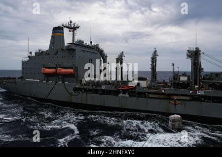 PHILIPPINISCHES MEER (Feb 14, 2022) der militärische Sealift Command Replenishment Oiler USNS Yukon (T-AO 202) führt einen Replenishment-at-Sea mit dem Ticonderoga-Klasse geführten Raketenkreuzer USS Mobile Bay (CG 53) durch. Die Abraham Lincoln Strike Group befindet sich im geplanten Einsatzgebiet der US-Flotte für 7th, um die Interoperabilität durch Allianzen und Partnerschaften zu verbessern und gleichzeitig als reaktionsfähige Truppe zur Unterstützung einer freien und offenen Region im Indo-Pazifik-Raum zu dienen. (USA Navy Foto von Mass Communication Specialist 3rd Class Alonzo Martin-Frazier) Stockfoto