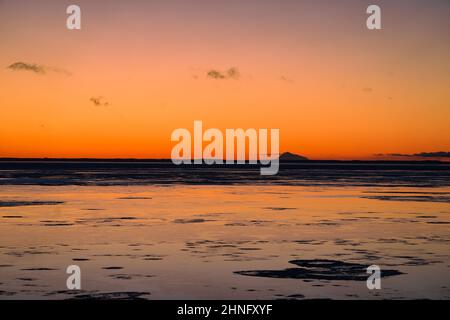 Der Sonnenuntergang leuchtet über dem Cook Inlet und hinter dem Mount Redoubt von Anchorage, Alaska. Stockfoto