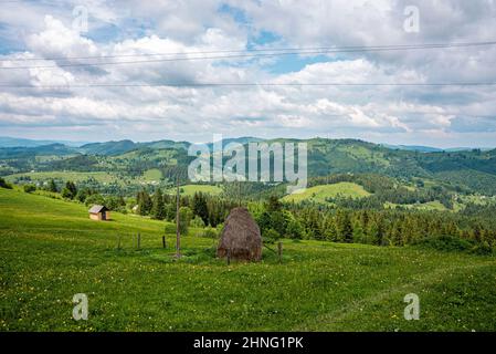 Heuhaufen auf der Alm vor landschaftlich reizvoller Aussicht auf die Bergkette Stockfoto