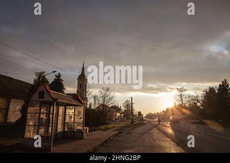 Bild der Hauptstraße, die das Dorf Banatsko novo selo, in der Vojvodina, in der Region Banat durchquert, mit Menschen, Autos, die vor einem vorbeifahren Stockfoto