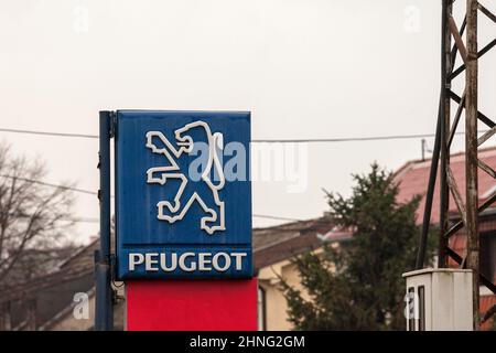 Bild eines alten Schildes mit dem ehemaligen Peugeot-Logo, neben einem Autohaus der Marke in Ostserbien. Peugeot ist ein französischer Automobilhersteller Stockfoto