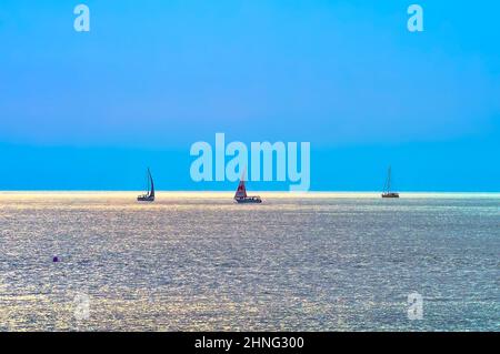 Adler, Sotschi, Russland, 11.01.2021. Yachten im Schwarzen Meer. Segelboote segeln am Horizont bei Sonnenuntergang ('Krasnaya Polyana' Segel) Stockfoto