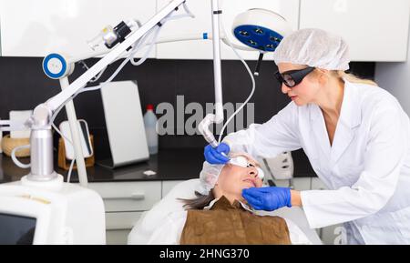 Kosmetologe tun Laser Warze Entfernung Verfahren für ältere Frau Stockfoto