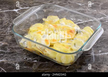 Gebackene Kartoffeln und Käse Auflauf in Glas Backform auf dem Tisch Stockfoto