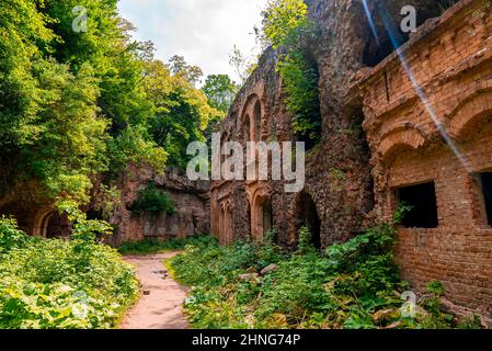 Fußweg durch alte verlassene Festung, umgeben von grünen Pflanzen an sonnigen Tagen Stockfoto