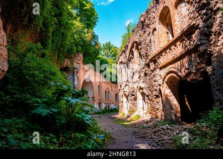 Fußweg durch alte verlassene Festung, umgeben von grünen Pflanzen an sonnigen Tagen Stockfoto