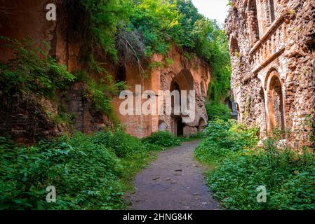 Fußweg durch alte verlassene Festung, umgeben von grünen Pflanzen an sonnigen Tagen Stockfoto