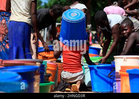 Ein junges Mädchen nutzt einen Eimer, um sich vor der sengenden Sonne im Bangula-Camp für Menschen zu schützen, die vom Tropical Cyclone Ana im Bezirk Nsanje, Malawi, vertrieben wurden. Stockfoto