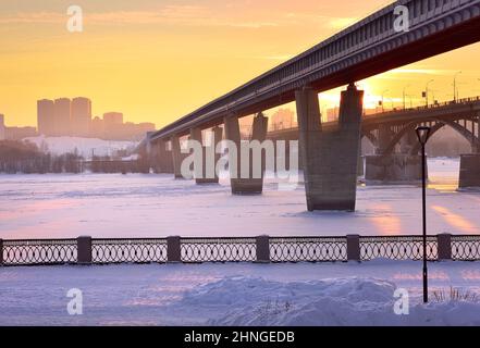 Winter Böschung am Abend. Die größte U-Bahn-Brücke der Welt über den ob River, bedeckt mit Eis und Schnee. Nowosibirsk, Sibirien, Russland, 2022 Stockfoto