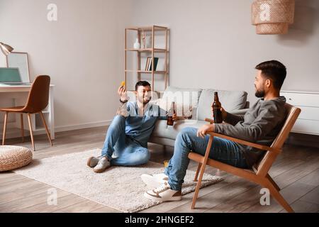 Männliche Freunde mit Bierflaschen haben Spaß zu Hause Stockfoto