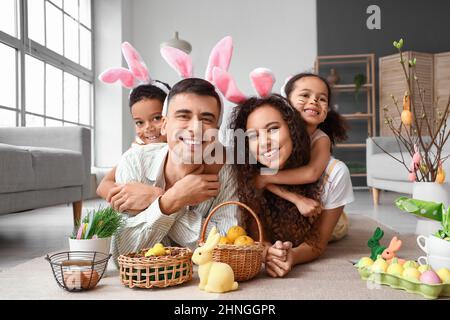 Glückliche Eltern mit ihren kleinen Kindern in Hasenohren zu Hause Stockfoto