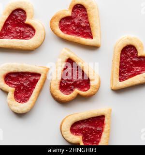 Draufsicht auf herzförmige, mit Himbeeren gefüllte Linzer Cookies. Stockfoto