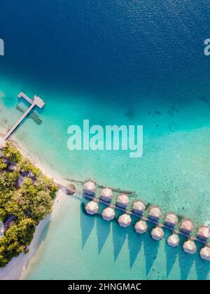 Überwasser-Villen und weißer Sandstrand auf einer tropischen Insel für Urlaubsreisen und Flitterwochen. Luxus-Resort-Hotel auf den Malediven oder der Karibik mit Stockfoto