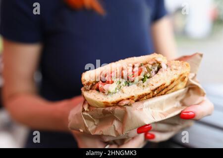 Frau hält ein Sandwich mit Füllung in den Händen Stockfoto