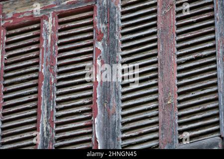 Altes traditionelles Landhaus verwitterte hölzerne Fensterläden mit abgebrochenem Lack in Nafplio, Griechenland. Stockfoto
