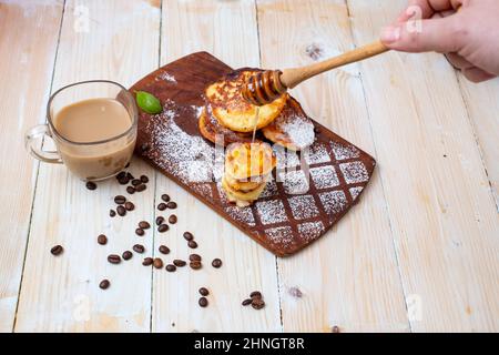 Käsepfannkuchen mit Kaffee auf einem Holzhäcksler. Hausgemachtes Frühstück. Stockfoto