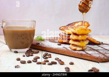 Käsepfannkuchen (rumänischer Papanasi) mit Kaffee auf einem Holzhacker. Hausgemachtes Frühstück. Stockfoto