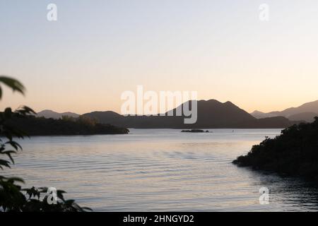 Berglandschaft auf Inseln mit Sonnenlicht, das bei Sonnenuntergang von der Wasseroberfläche reflektiert wird Stockfoto