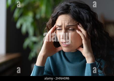 Ermüdete überarbeitete junge Frau, die an Migräne litt und sich um persönliche Probleme sorgte Stockfoto
