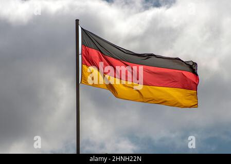 Im berühmten Reichstagsgebäude, dem Sitz des Deutschen Bundestages, winken deutsche Flaggen im Wind an einem sonnigen Tag mit blauem sk Stockfoto